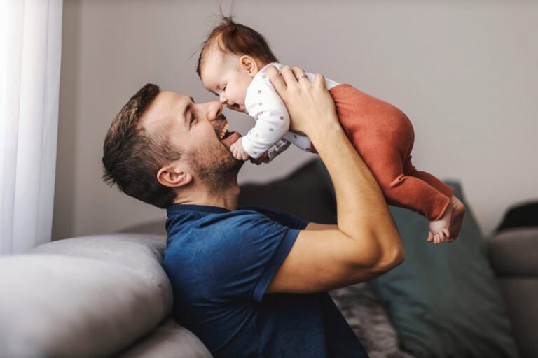 Father smiling at baby girl and lifting her in the air