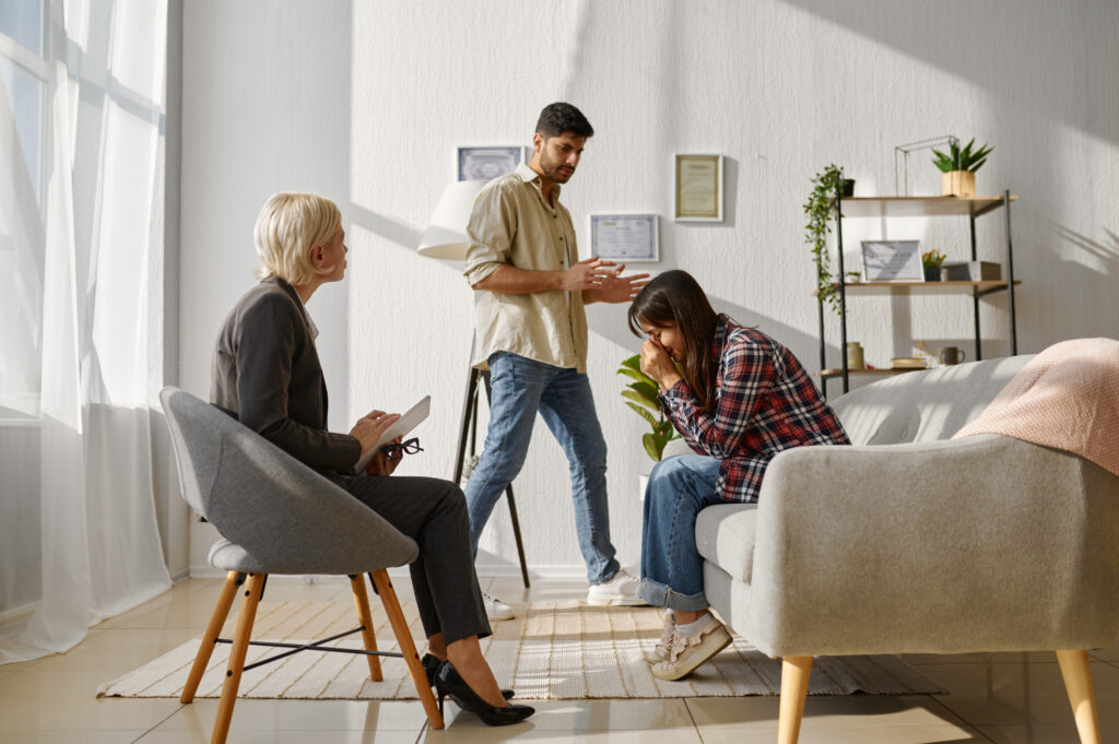 A couple in counselling, the man is talking while the woman looks upset