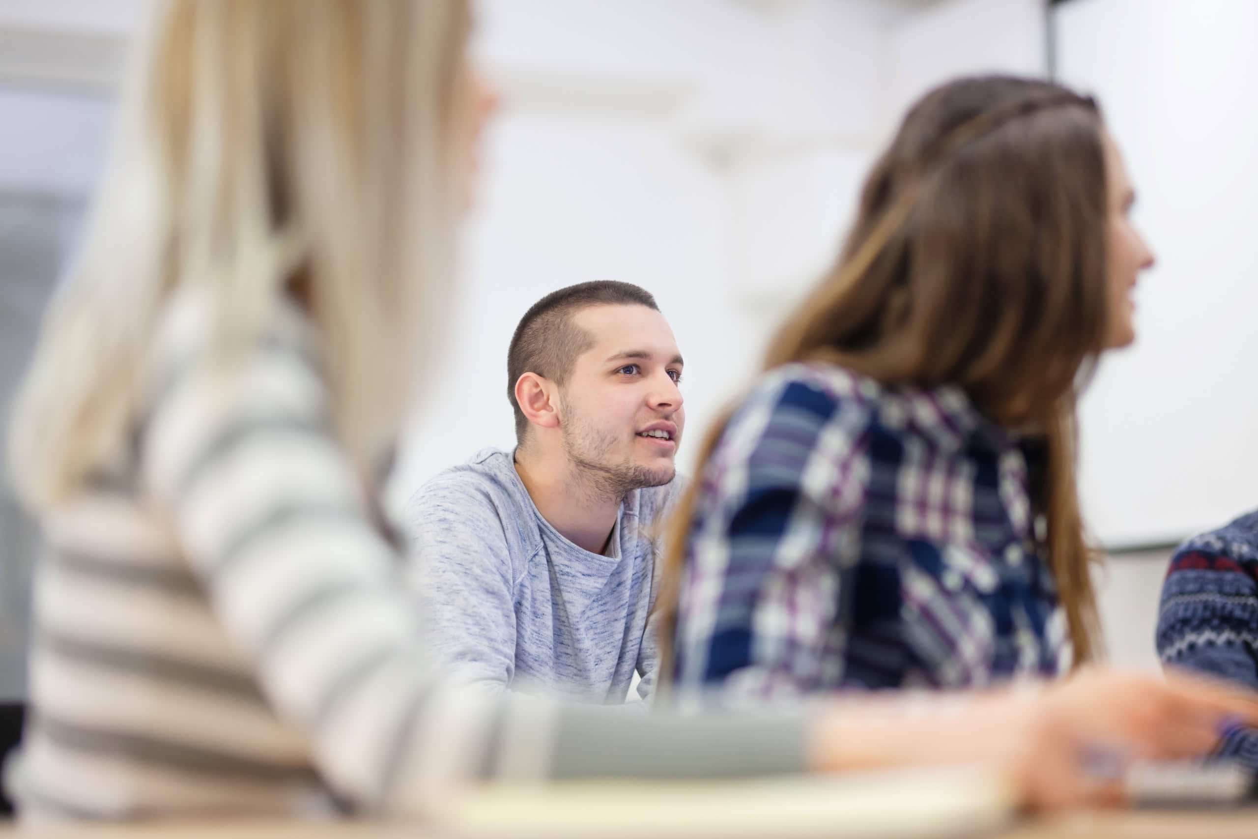 A group of students sitting at a table in a classroom.